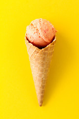 Tasty fresh fruity ice cream in ice cream cone on yellow vibrant background.