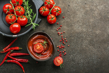 Dark ceramic bowl with tomato sauce, fresh vegetables, herbs, pepper on a dark background. Top View.