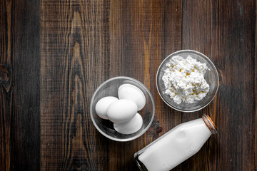 Farm products. Milk,cottage, eggs on dark wooden background top view copyspace