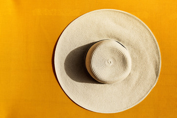 Beautiful straw hat on yellow vibrant vivid background. Top View.