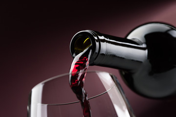 Pouring red wine into a wineglass - obrazy, fototapety, plakaty