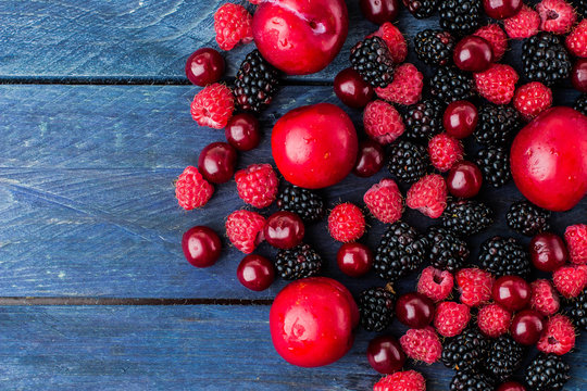 Food Background. Summer fresh berries on blue wooden table background. Copy space. Top view Vegetarian food - raspberry, blackberry and cherry. Rustic style