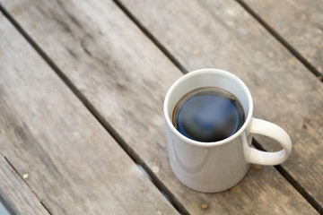 White cup of black coffee on wooden table