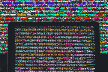 Laptop screen with source code in front of the bigger display