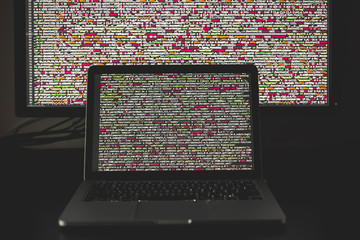 Laptop screen with source code in front of the bigger display