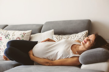Young pregnant woman, having painful contraction, starting labor