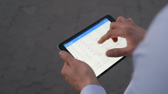 Man hands holding tablet using touch screen graphs charts working device laptop calculations resume technology tapping touching business summing up networking keeping statistics successful outcome