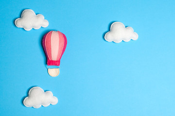 Obraz premium Hot air balloon in blue sky with clouds, frame, copyspace. Hand made felt toys.