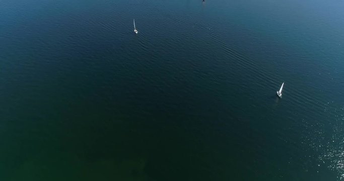 Yachts on baltic sea, Cinema 4k aerial tilt up view above the baltic sea and towards a group of colorful sailboats, out on the turquoise sea, on hango regatta day, in the finnish archipelago