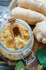 Ground ginger in a glass jar and ginger root.