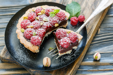 Piece of tartlets with chocolate and raspberry on a fork.