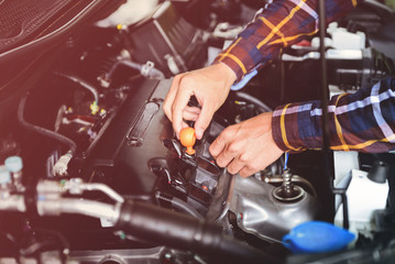 Close up hands checking lube oil level of car engine from deep-stick for service and maintenance concept vintage tone