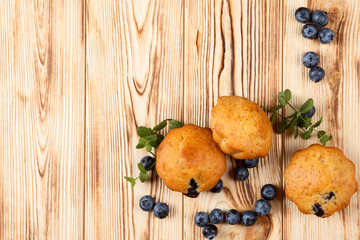 Homemade baked muffin with blueberries, fresh berries, mint on wooden background. Empty space for text.