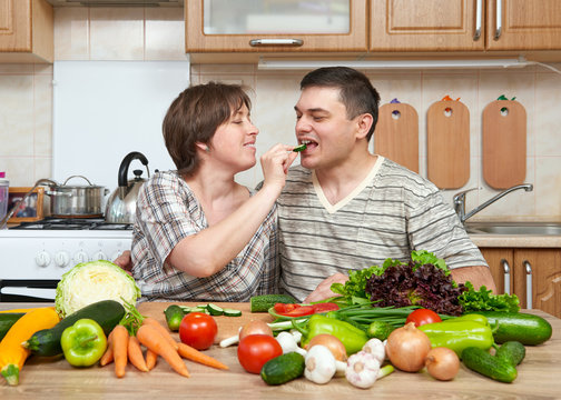 couple cooking in kitchen interior with fresh fruits and vegetables, healthy food concept, woman and man