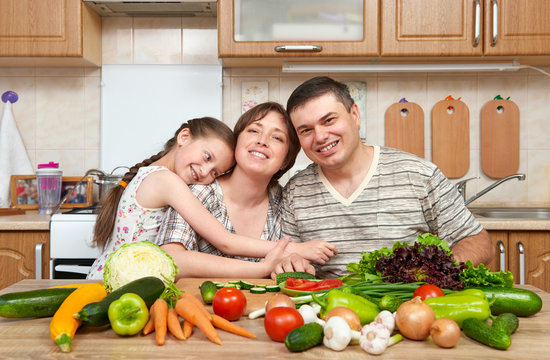 family cooking in kitchen interior at home, fresh fruits and vegetables, healthy food concept, woman, man and children