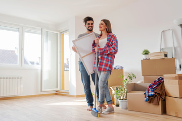 Young couple unpacking and cleaning empty apartment - relocation, moving.