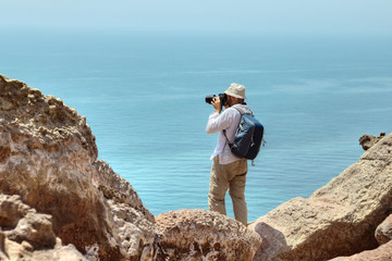 Tourist photographing nature, standing on the edge of a cliff.