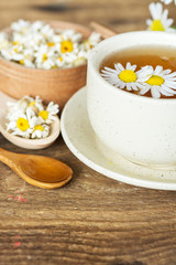 Obraz na płótnie Canvas cup of herbal chamomile tea with fresh daisy flowers on wooden background. doctor treatment and prevention of immune concept, medicine - folk, alternative, complementary, traditional medicine 