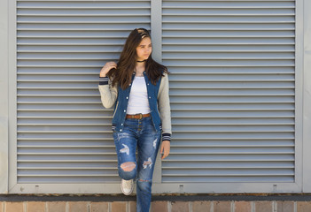 A girl stands near a fence of blinds