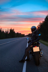 Fototapeta premium Tired motorcyclist resting on roadside when travel on motorcycle at night time