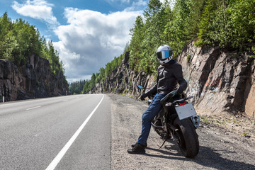 Obraz premium One motortraveler with own motorbike resting on roadside on the mountain asphalt road
