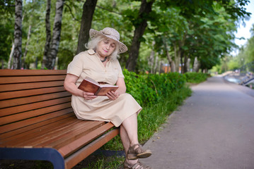 Fototapeta premium An elderly woman reads a book in the park