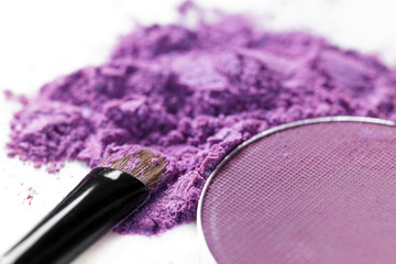 crushed purple eye shadow and makeup brush isolated on white background