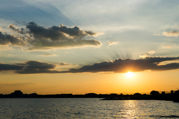 Sun behind the clouds and sunbeams in the sky over the waters of Black Sea, Burgas bay, Bulgaria
