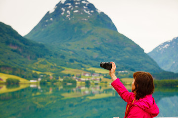 Fototapeta na wymiar Tourist taking photo at norwegian fjord lake