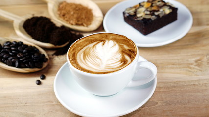 Latte art and cappuccino with Rosetta leaf and flowers made from milk on the wood table with roasting coffee beans. Beverage and breakfast or food and drink menu with hot coffee at the cafe shop.