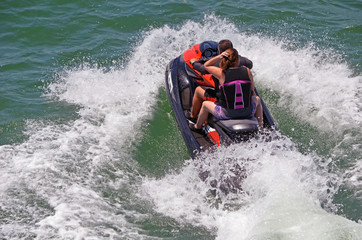 Couple riding tandem on a speeding jet ski on the florida intra-coastal waterway near Miami Beach.