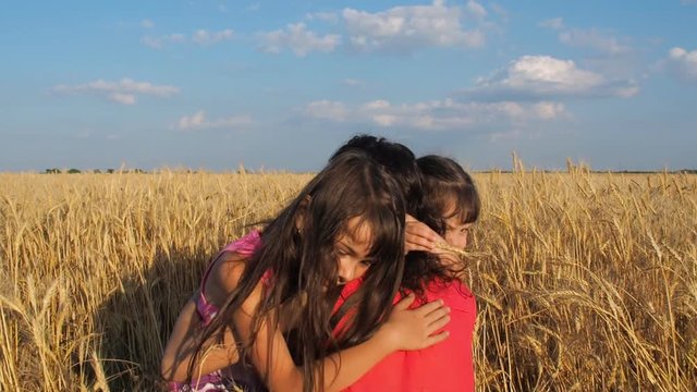 Children are hugging their mother on a wheat field. Happy daughters hug Mom.