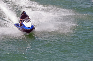 Fototapeta na wymiar Angled overhead view of a man on a speeding jet ski riding waves on the florida intra-coastal waterway off Miami Beach.