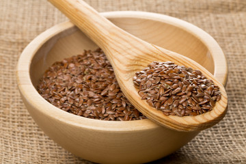 Raw, unprocessed linseed or flax seed in wooden bowl and wood spoon