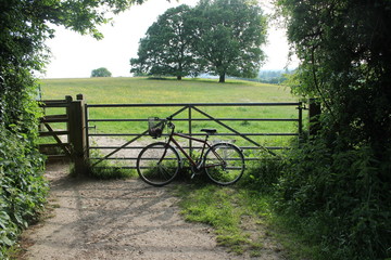 push bike bicycle with basket resting against farm gate in countryside Sussex uk, travel explore...