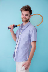 Portrait of american man standing sports with tennis racket ion pink background.