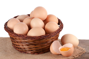 eggs on a wooden table in a wicker basket on a white background