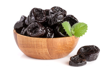 Dried plums or prunes with a mint leaf in wooden bowl isolated on white background