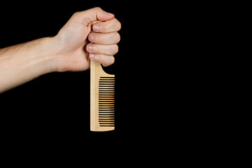 Fototapeta na wymiar The fist wooden comb inverted tooth down, isolated on black background