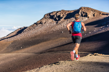 Trail runner man running with backpack on volcano mountain. Ultra marathon race athlete on volcanic path run in mountains landscape.