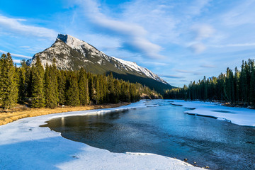 right mountain peak with snow and icy river