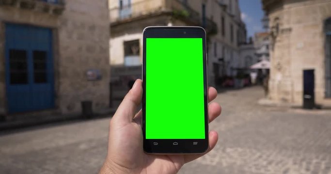 POV walking in the cobblestone streets in Havana, Cuba while holding a green screen smartphone. With optional corner markers for advanced tracking.  	
