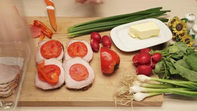 Human hands making sandwich. Table wooden board full of fresh food vegetables. Time lapse 4K ProRes HQ codec