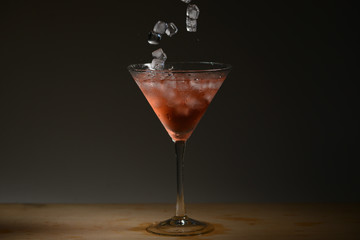 Falling ice cubes on blood mary cocktail in dark background