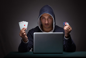 Young man wearing a hoodie sitting in front of a laptop computer