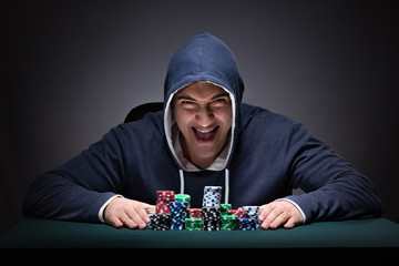 Young man wearing a hoodie with cards and chips gambling