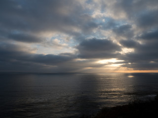 Beams of sunlight show through a cloudy sky onto the ocean