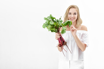 Beautiful blond woman holds beetroot with green leaves on white background. Health and vitamins