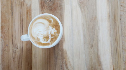 Hot cappuccino or latte art. A cup of coffee on the wooden table with dark roasted beans. Morning...