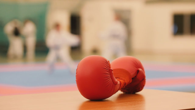 Red karate gloves on tatami during training, de-focused